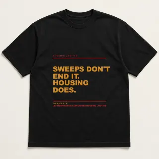 Front of a black tee reading "Sweeps don't end it. Housing does." with the Housing Justice page address printed under it